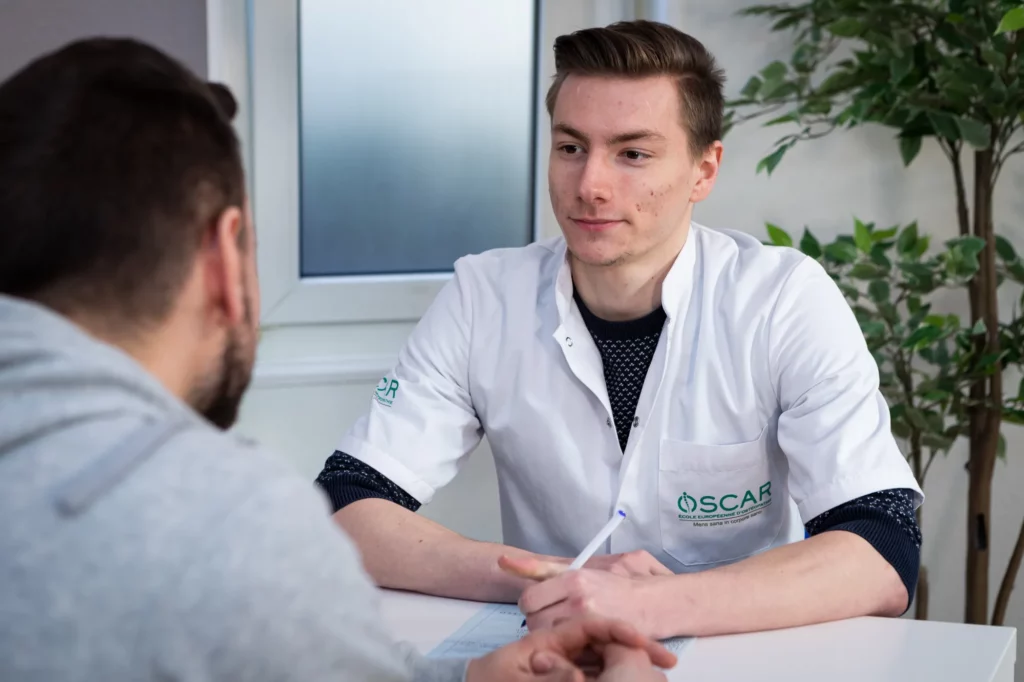 Étudiant en ostéopathie parlant avec un patient en consultation