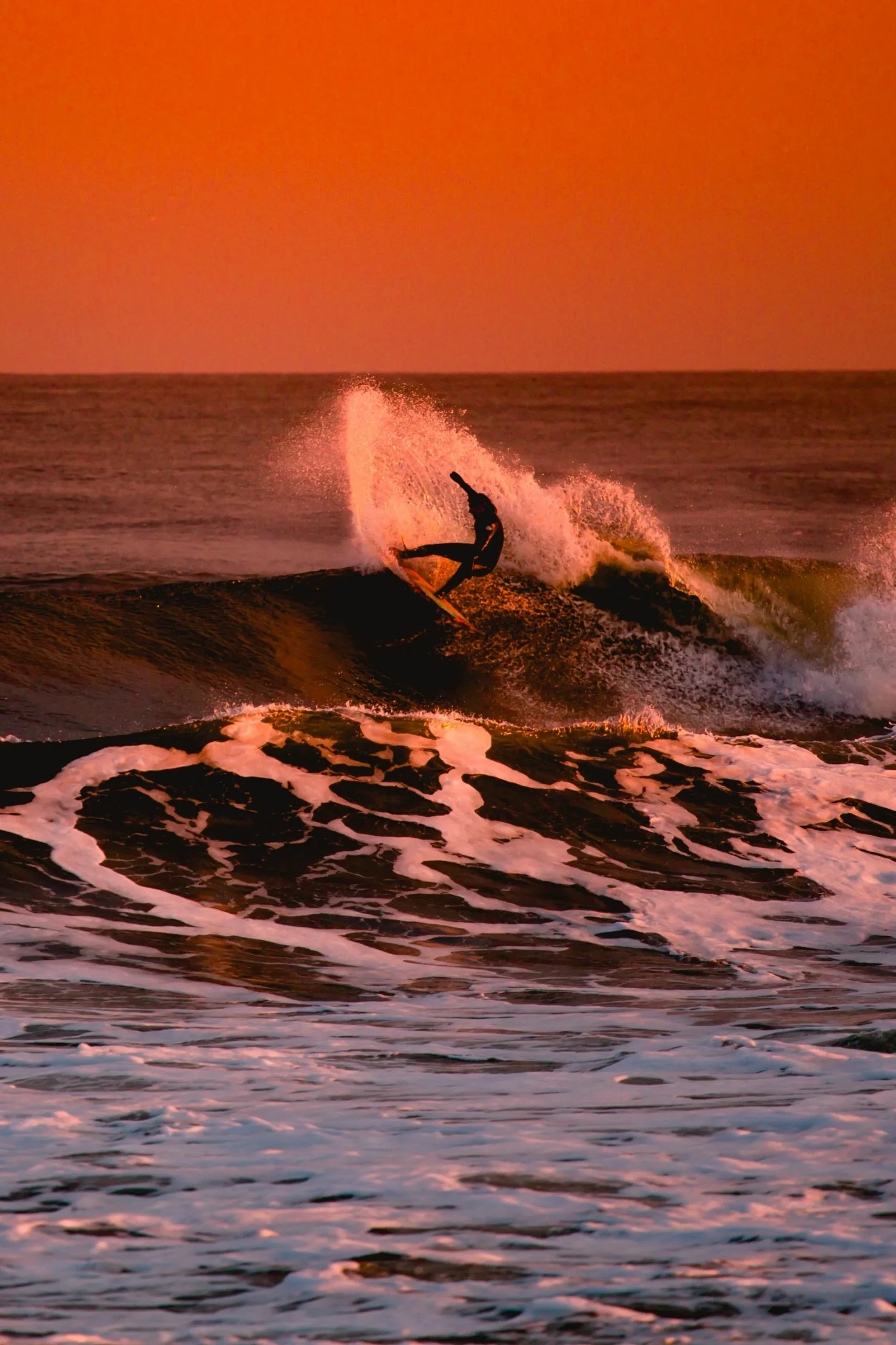 surfeur sur une vague au coucher de soleil